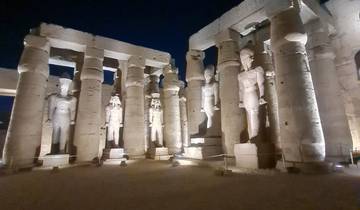 Statues on an illuminated ancient structure at night.