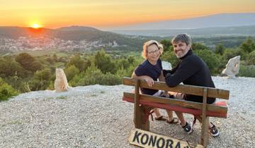 Couple sitting on a bench with scenic sunset view over a valley.