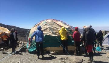 Group of people setting up a large tent at high altitude.