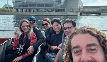 Group of people on a boat ride with modern building backdrop.