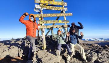 Happy hikers at Uhuru Peak with a sign.