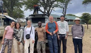 Group of people posing next to a safari vehicle.