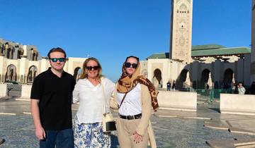 Three people posing in front of a mosque.