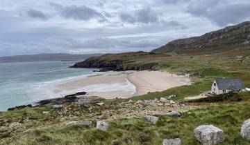 Sandy beach with rolling hills in the background.