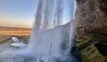A waterfall in a picturesque landscape with distant fields.