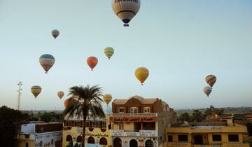 Hot air balloons over rooftops at dawn.