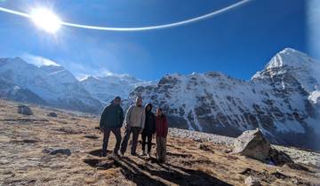 Group posing on a snowy mountain with a clear sky.