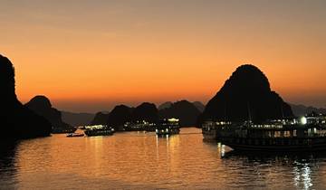 Sunset over Halong Bay with boats and limestone karsts
