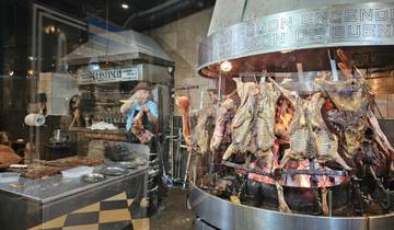 Open fire grill with various meats cooking in a traditional restaurant.