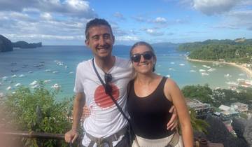 Couple smiling with a scenic beach view in the background.