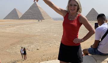Person posing with pyramids in the background.