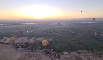 Aerial view of fields and hot air balloons at sunrise.