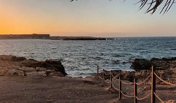 Sunset by the sea with distant buildings.