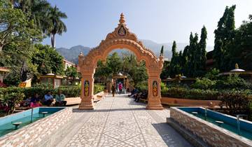 Decorative archway leading to a garden with mountains in the background.
