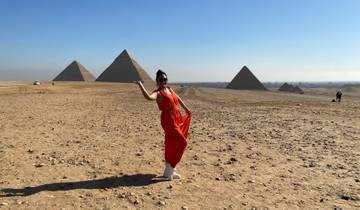 Person in a red dress posing with the Pyramids of Giza in the background.