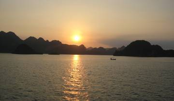 Sunset at Halong Bay with boat silhouette.
