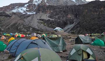 Camp site with colorful tents at the foot of a mountain.