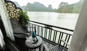 Private cruise balcony with chairs overlooking the water and rocky outcrops.
