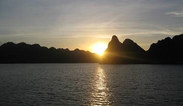 Sunset over the ocean with silhouetted hills.