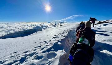 People trekking on a snowy mountain with clear skies.