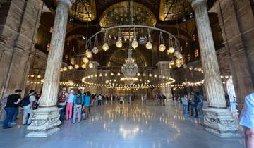 Interior of a mosque with decorative lights and visitors.