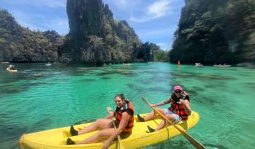 Two people kayaking in crystal-clear water surrounded by cliffs.