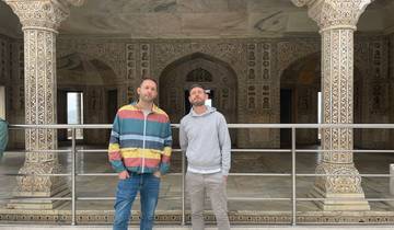 Two men standing in front of a marble structure with decorative pillars and arches.