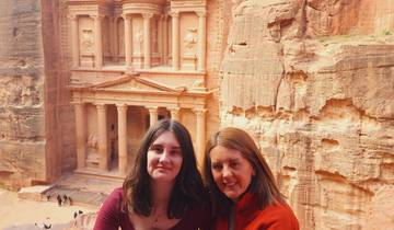 Two people sitting in front of Petra's iconic rock-cut architecture.