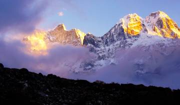Sunlit mountain peaks partially covered by clouds.