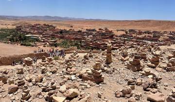 Panoramic view of a desert village with stacked rocks in the foreground.