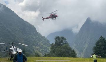 Helicopter flying over mountainous landscape with people below.
