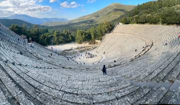 Ancient Greek amphitheater surrounded by lush mountains.