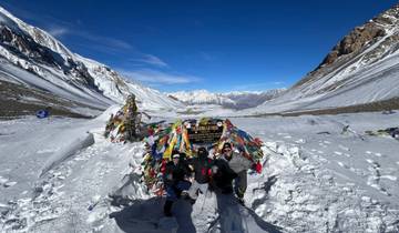 Group posing on snowy landscape with prayer flags