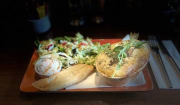 A meal consisting of a pie, salad, and bread on a wooden table.