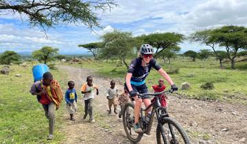Cyclist and children on a dirt road with bicycles in rural landscape.