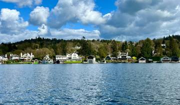 Lakeside houses with lush greenery and a cloudy sky.