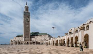 Large mosque with a tall minaret in an open courtyard with blue sky.