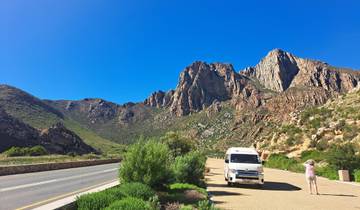 Person photographing a mountain range beside a road.