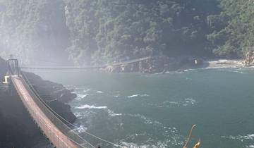 Suspension bridge over a misty coastal landscape.