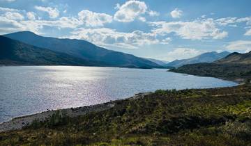 Expansive lake nestled among rolling hills and distant mountains.