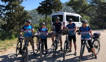 Group of cyclists posing on a sunny road with scenic background.