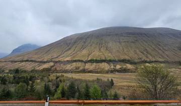 Mountain rising above a valley with hints of greenery.
