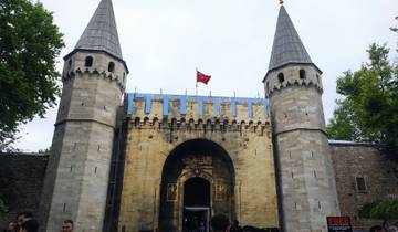 Entrance of a historical palace with a flag on top.