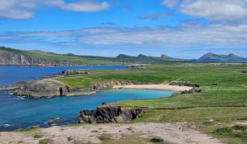 Coastal landscape with beach, cliffs, and grassy hills.