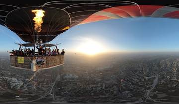 Hot air balloon with people onboard overlooking a vast landscape.
