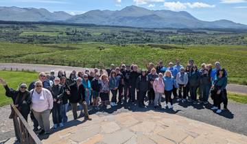Group of people posing with a scenic mountain landscape.