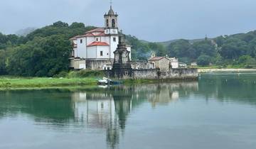 Historic church with a clock tower reflected in water.
