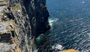 Rugged cliff overlooking a vibrant blue sea.
