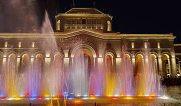 Colorful fountain show outside a historic building at night