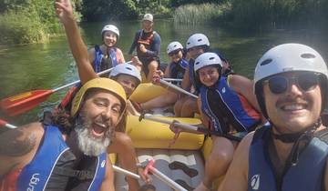 Group of people rafting on a river in a forested area.
